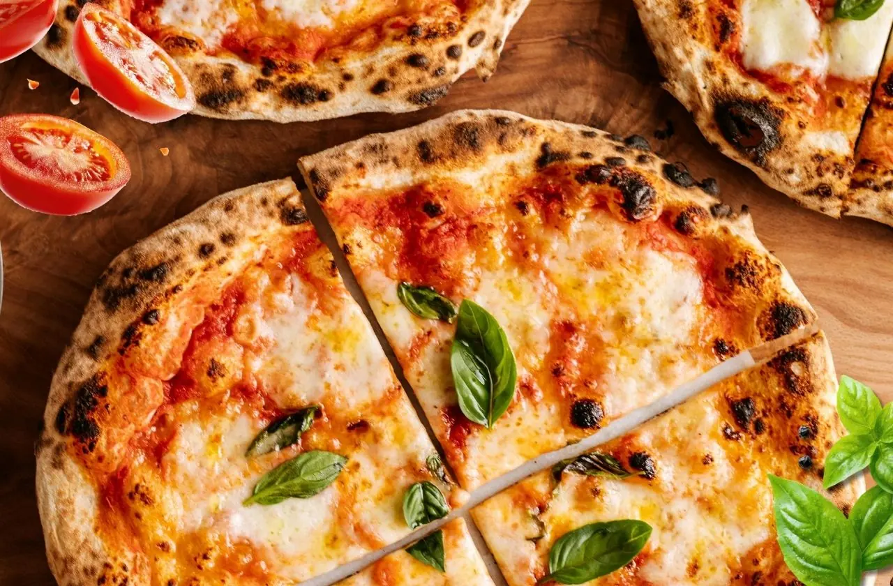 Pizzas margherita coupées en parts, posées sur une planche en bois